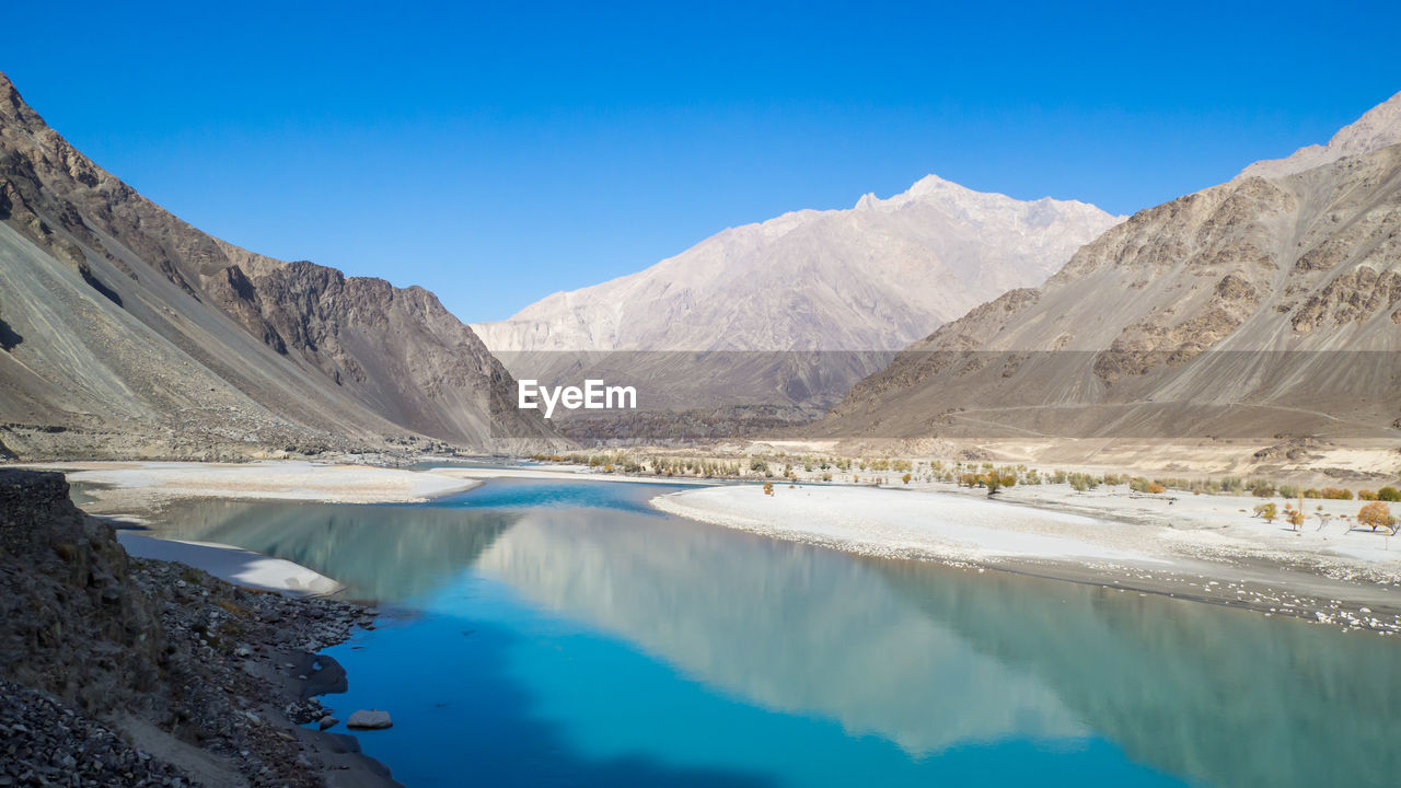 Panoramic view of lake and mountains against blue sky