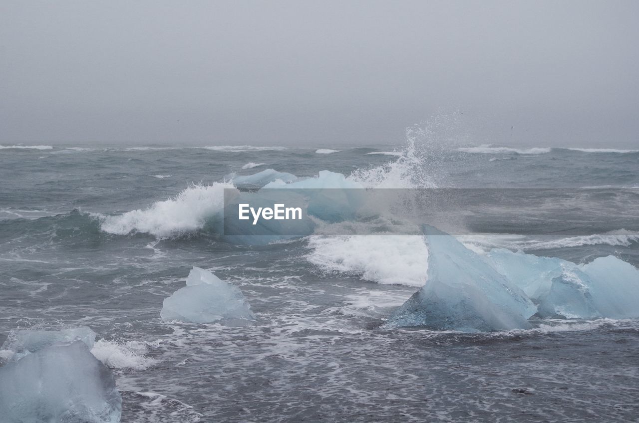 Scenic view of sea with icebergs against sky