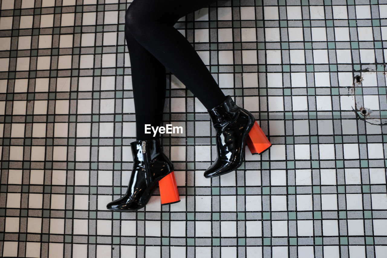 Low section of woman wearing high heels while lying on floor