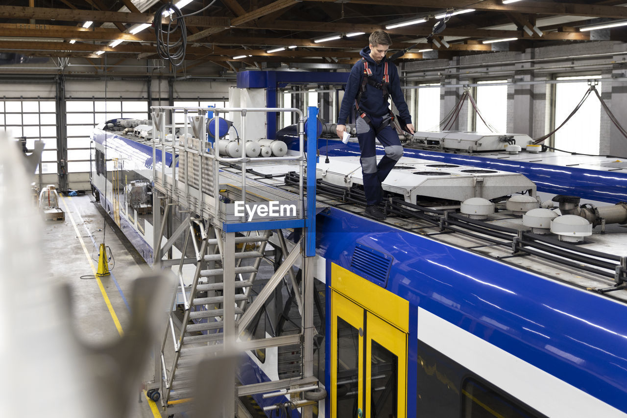 Engineer walking on monorail rooftop in factory