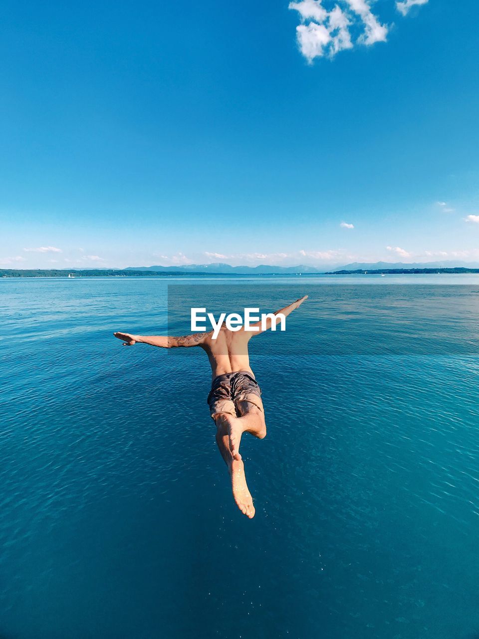 Full length of shirtless man diving into sea
