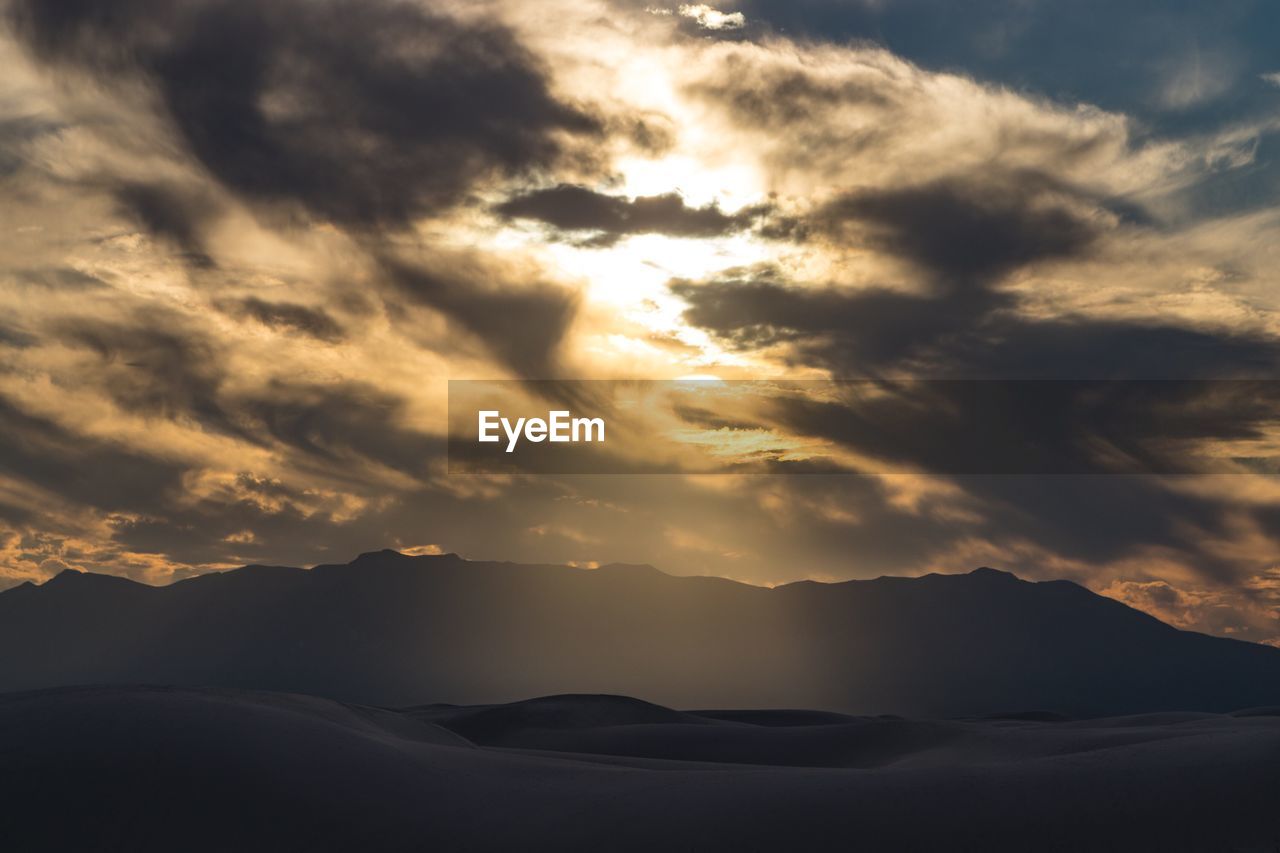 Scenic view of dramatic sky during sunset over white sand dunes