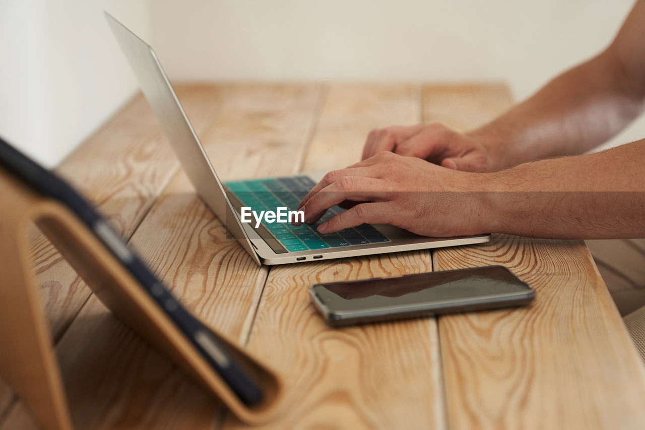 cropped hands using laptop at table