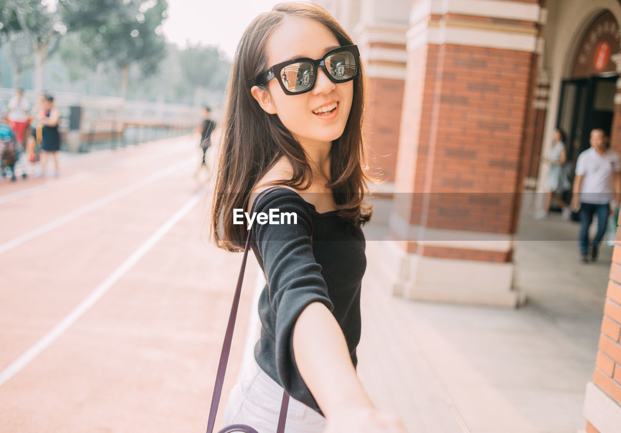 Portrait of young woman standing on footpath