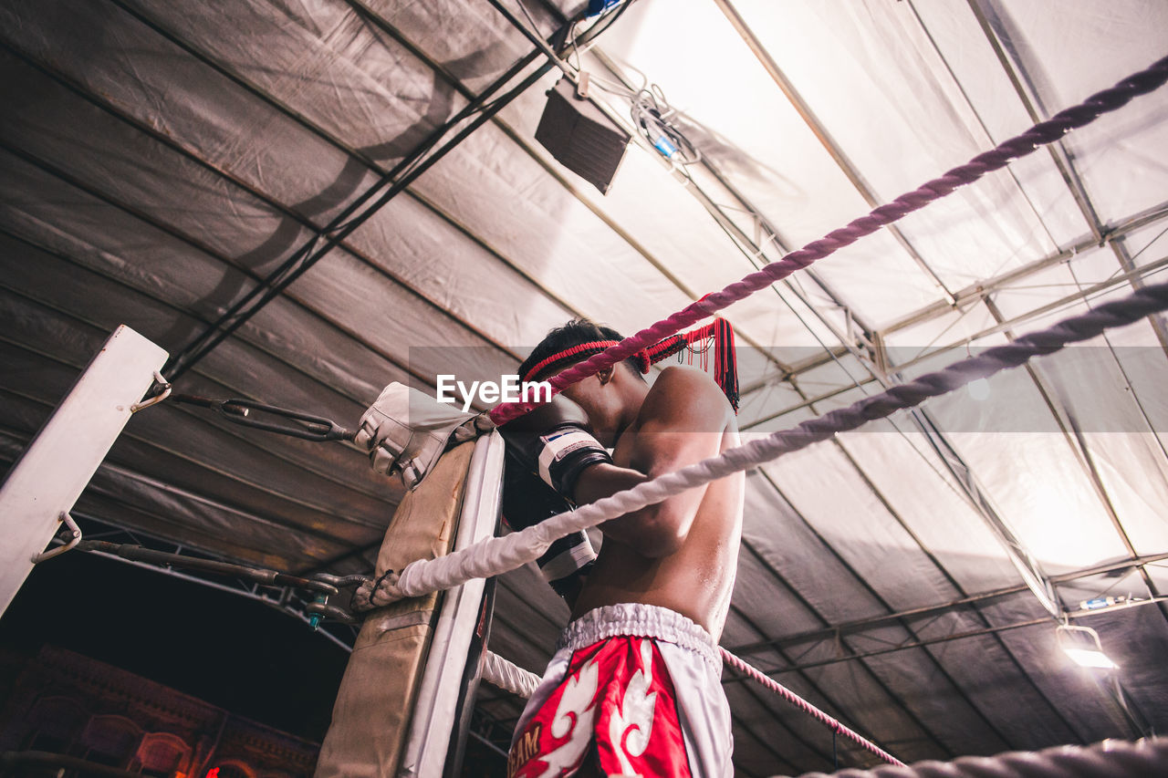 LOW ANGLE VIEW OF MAN WORKING AGAINST CEILING