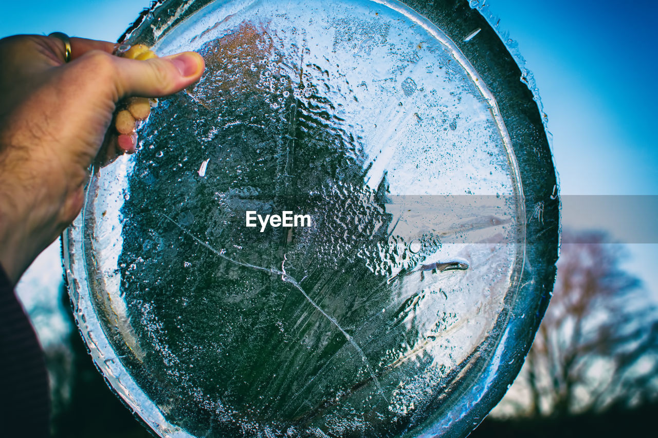 CLOSE-UP OF HAND HOLDING FISH AT AGAINST SKY