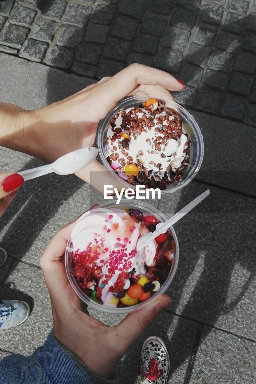 Cropped hands of people holding ice cream on road