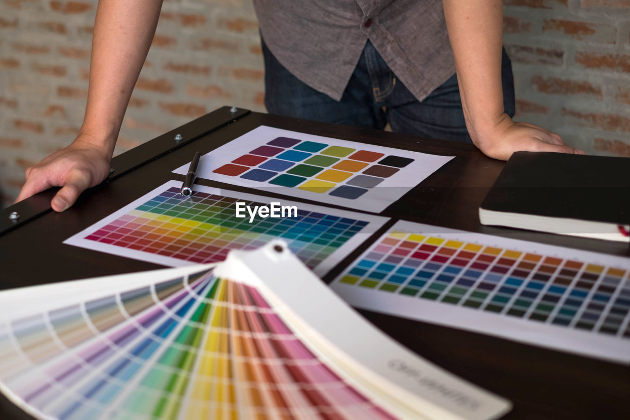 Midsection of design professional with color swatches on table