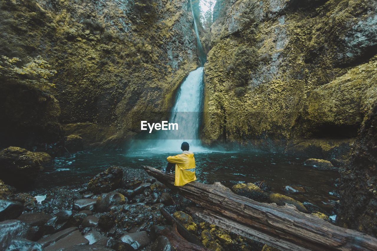 Rear view of man overlooking waterfall