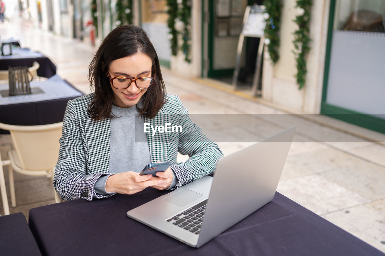 young woman using laptop while sitting on table