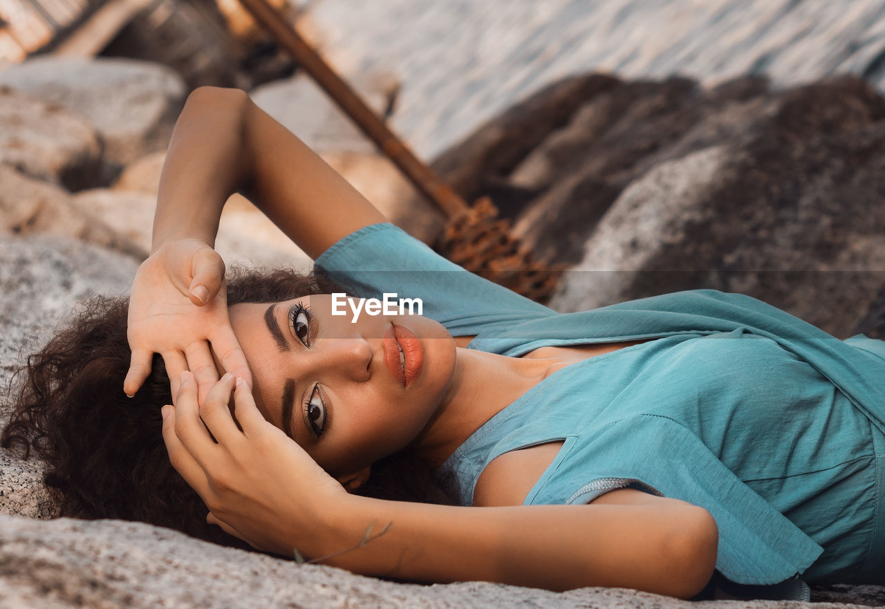 Portrait of young woman lying on rock