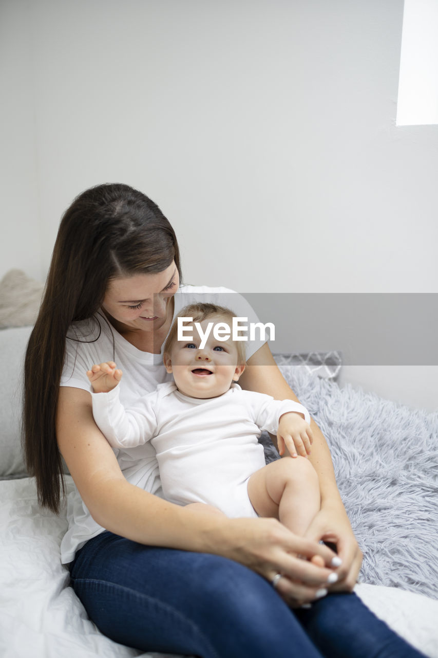 mother and daughter sitting on bed