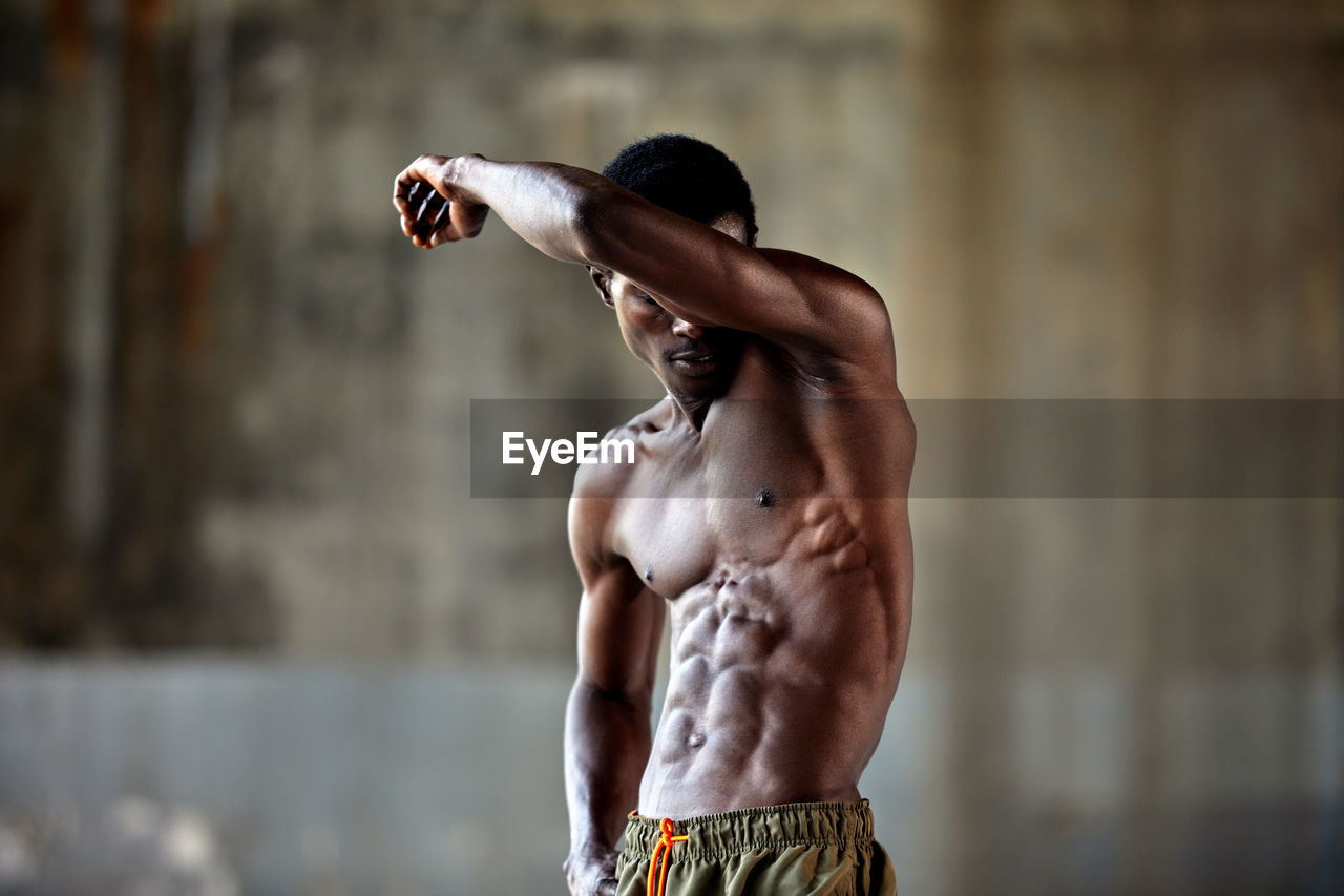 low angle view of shirtless man with arms raised