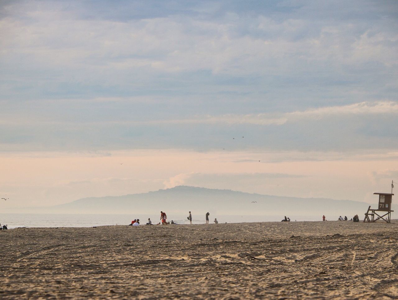 People on beach against sky during sunset