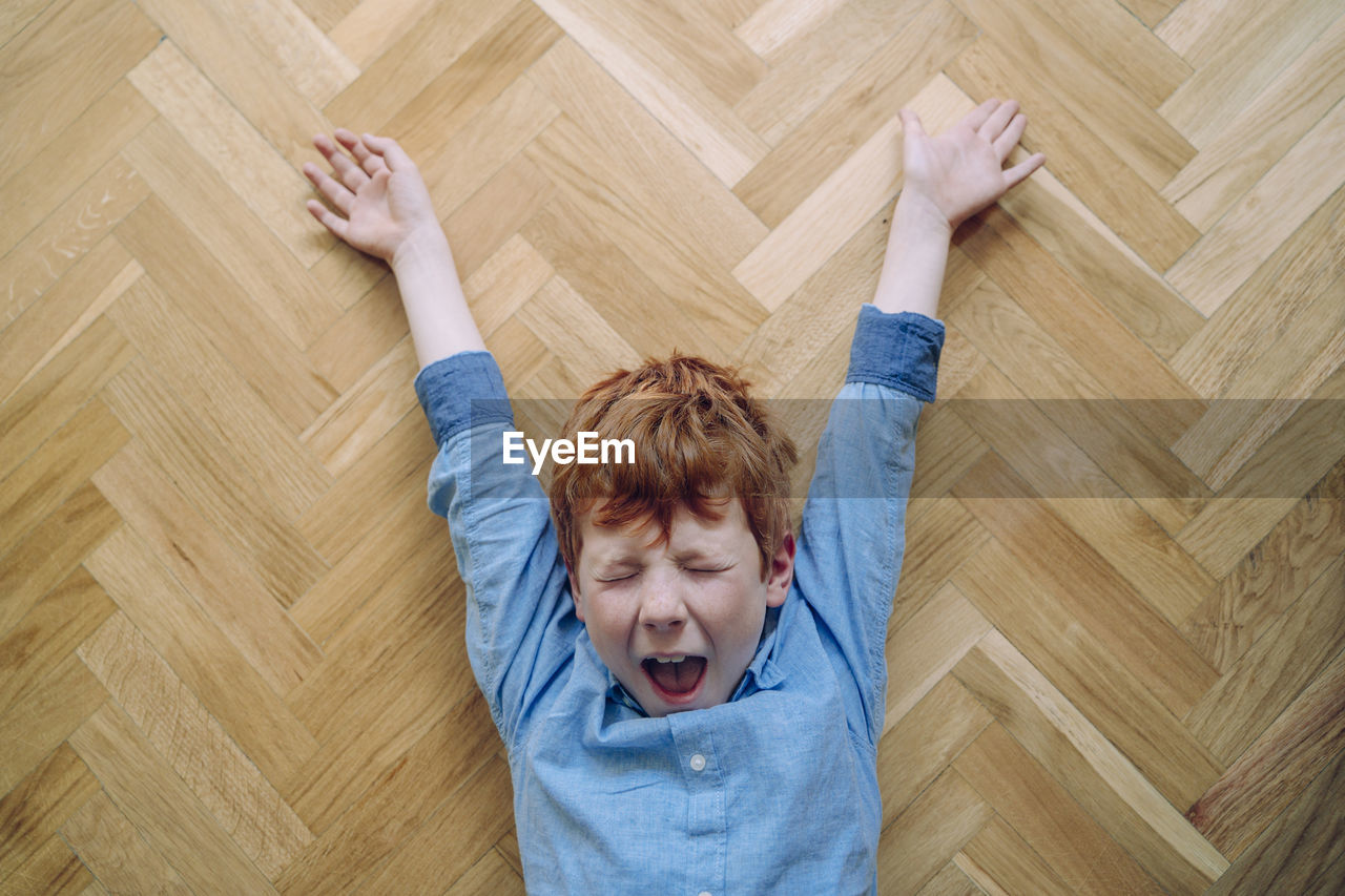 High angle view of boy lying on hardwood floor