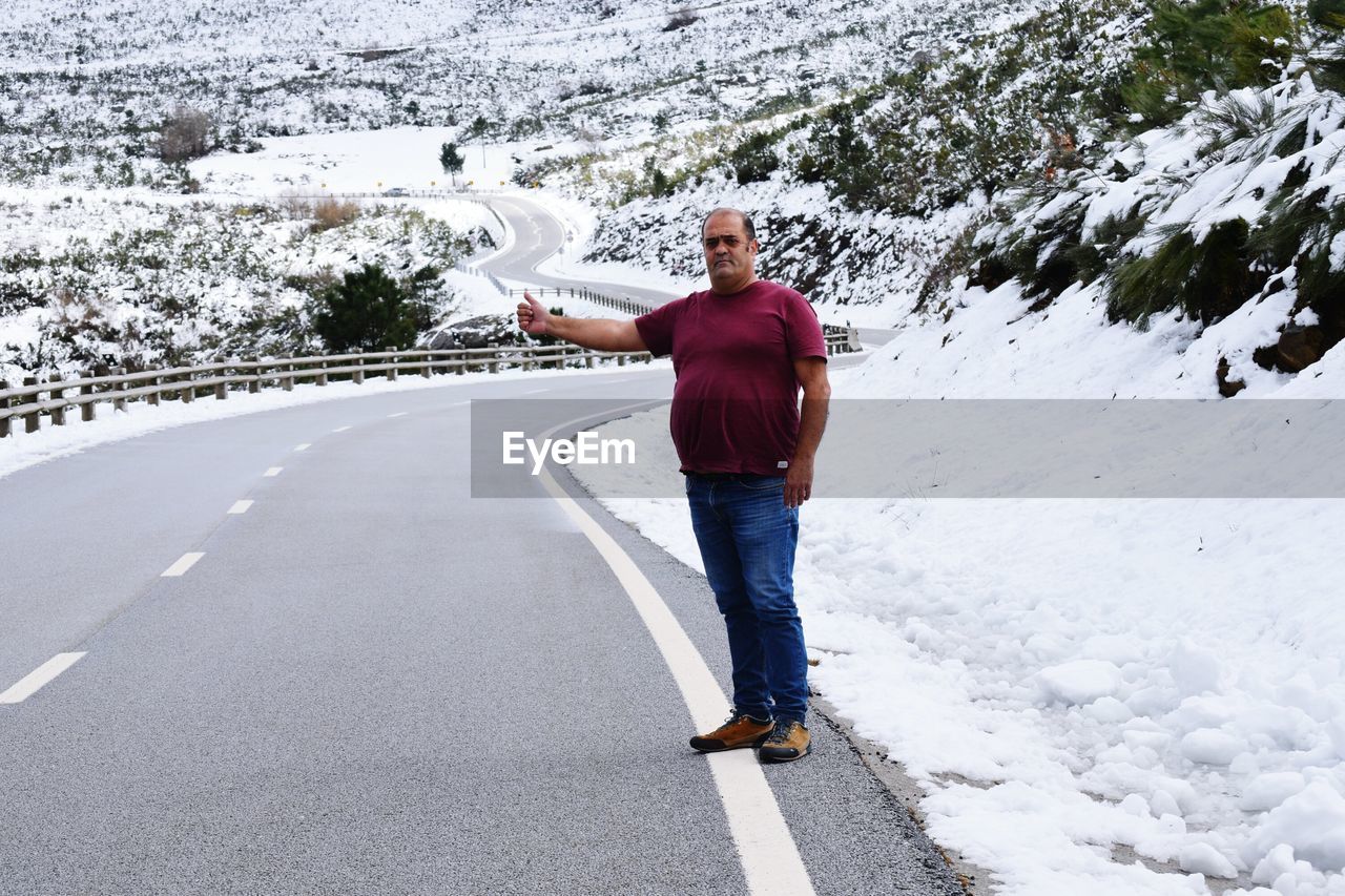 Portrait of man gesturing while standing on road during winter