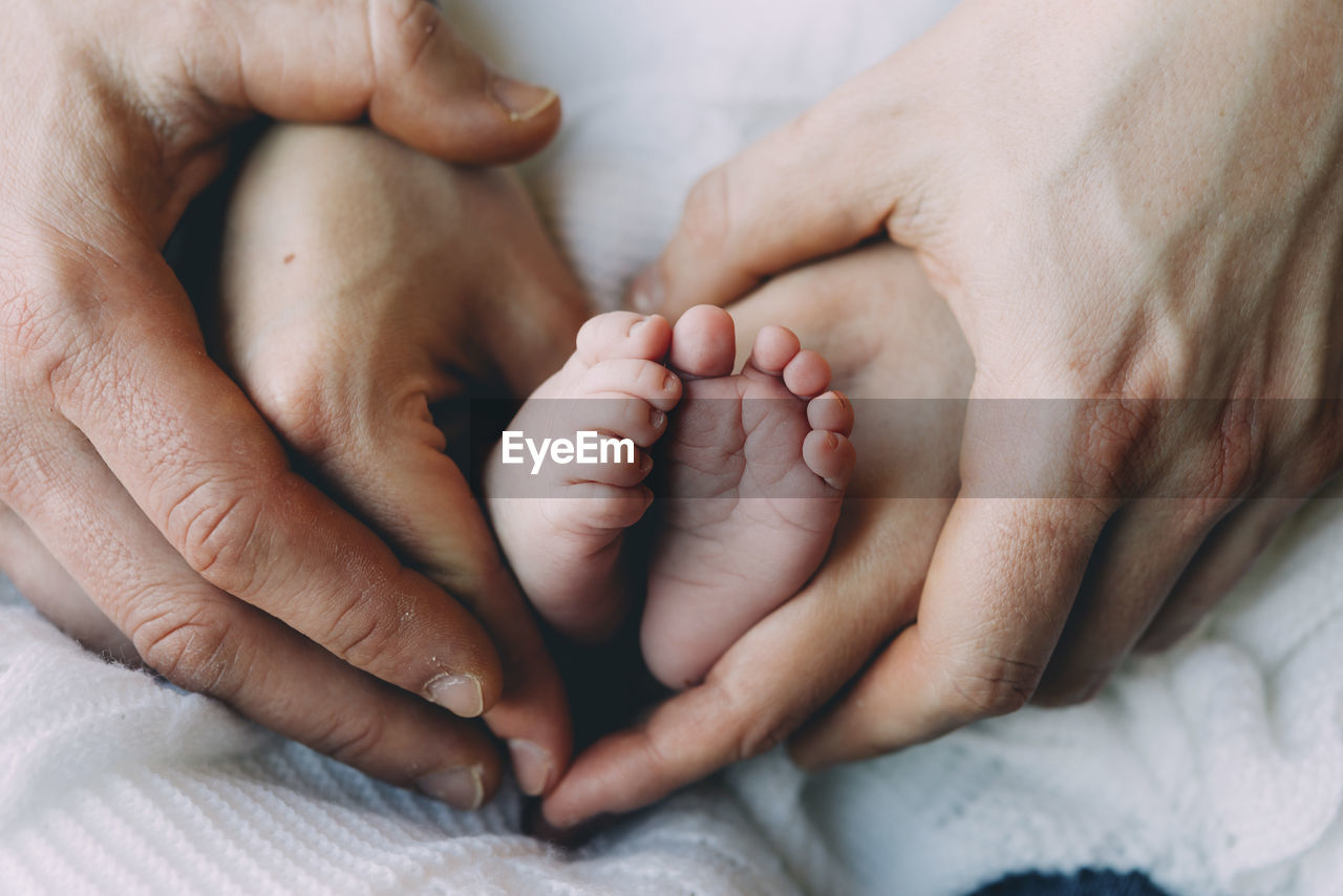 Father's and mother's hands holding baby's feet