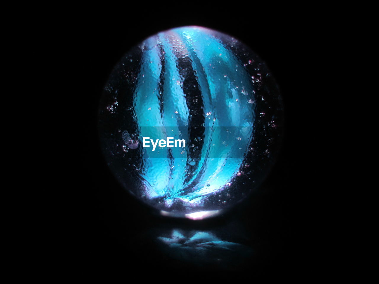CLOSE-UP OF ILLUMINATED BLUE LIGHT AGAINST BLACK BACKGROUND