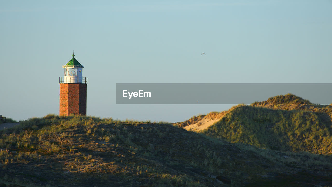 Lighthouse amidst buildings against sky