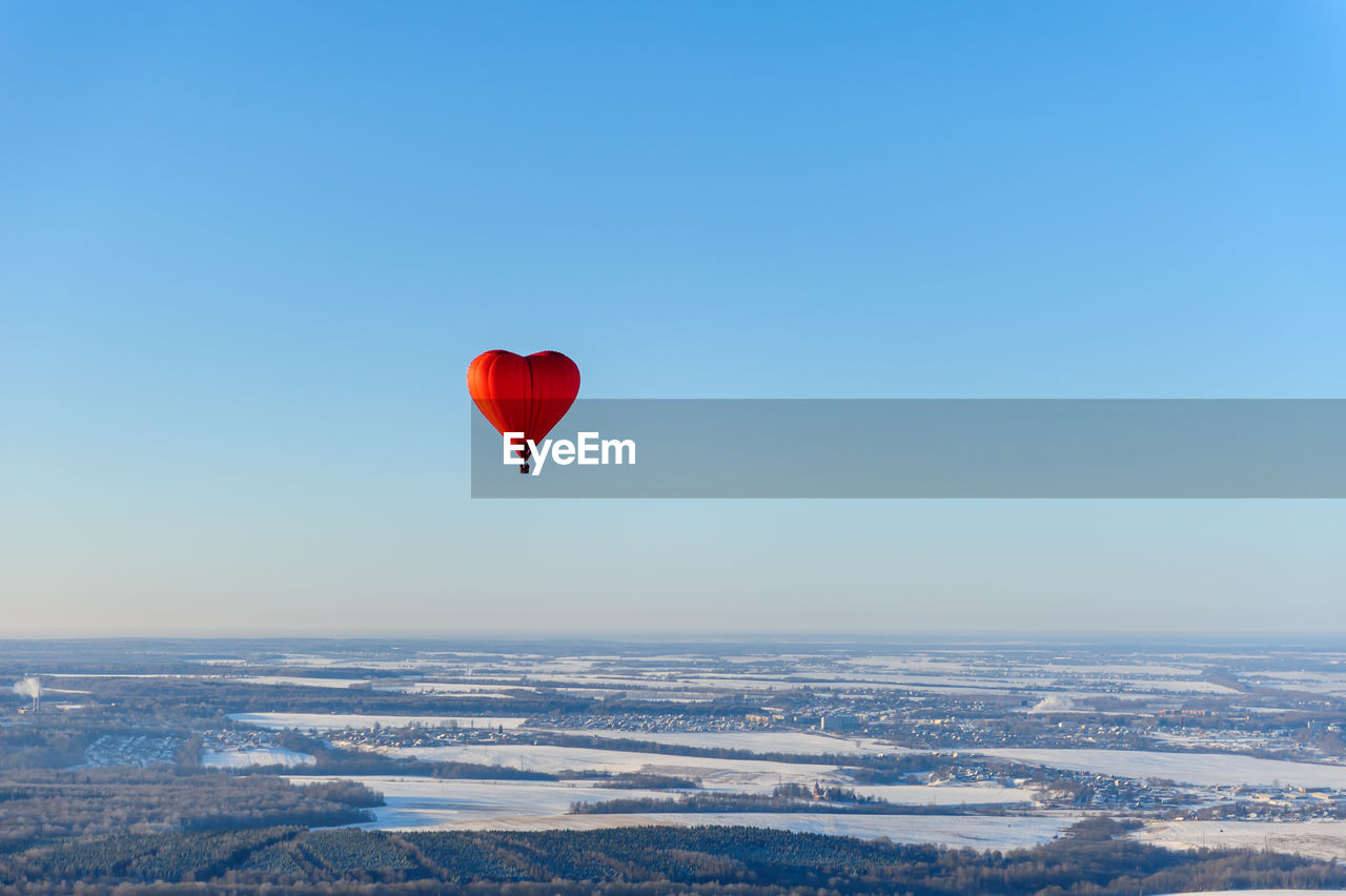 Aerial view of red heart shape hot air balloon against blue sky