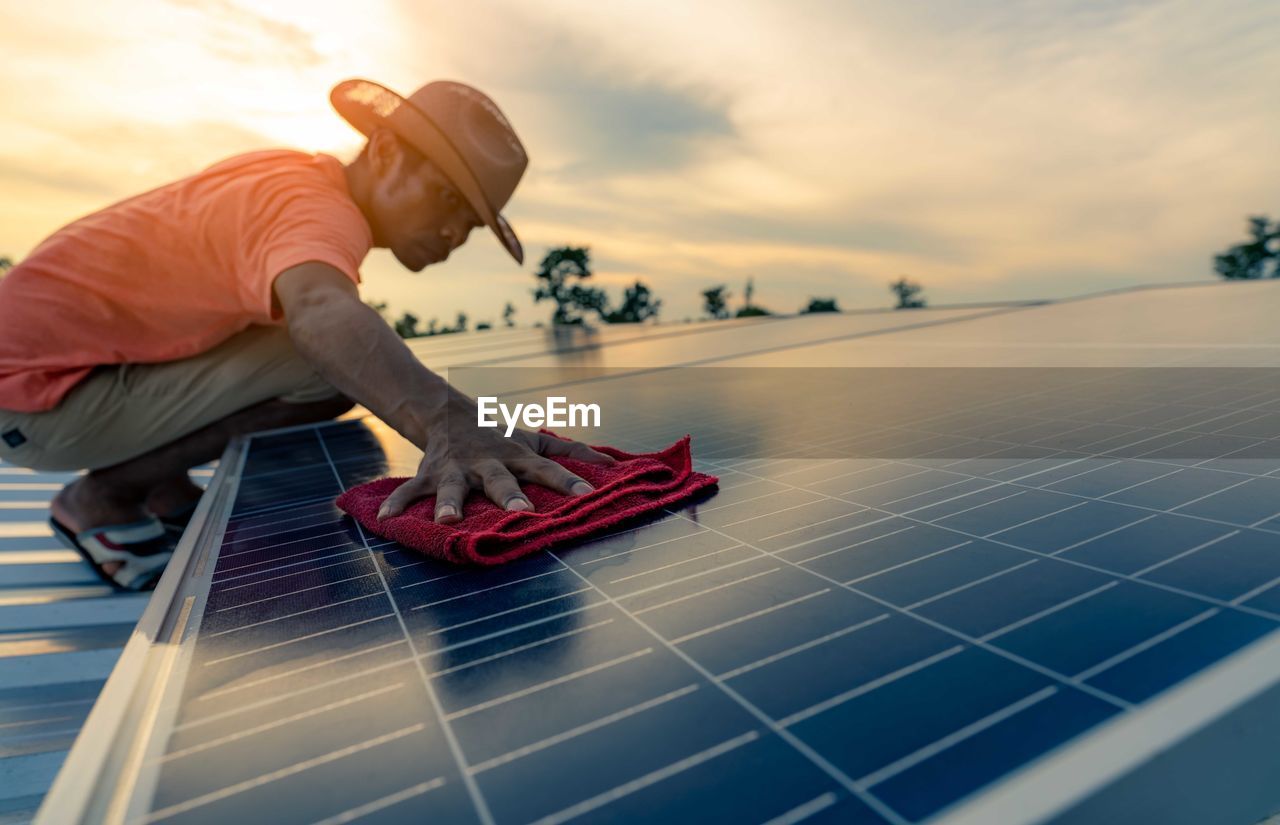 Man cleaning solar panel on roof. solar panel or photovoltaic module maintenance. sustainable.