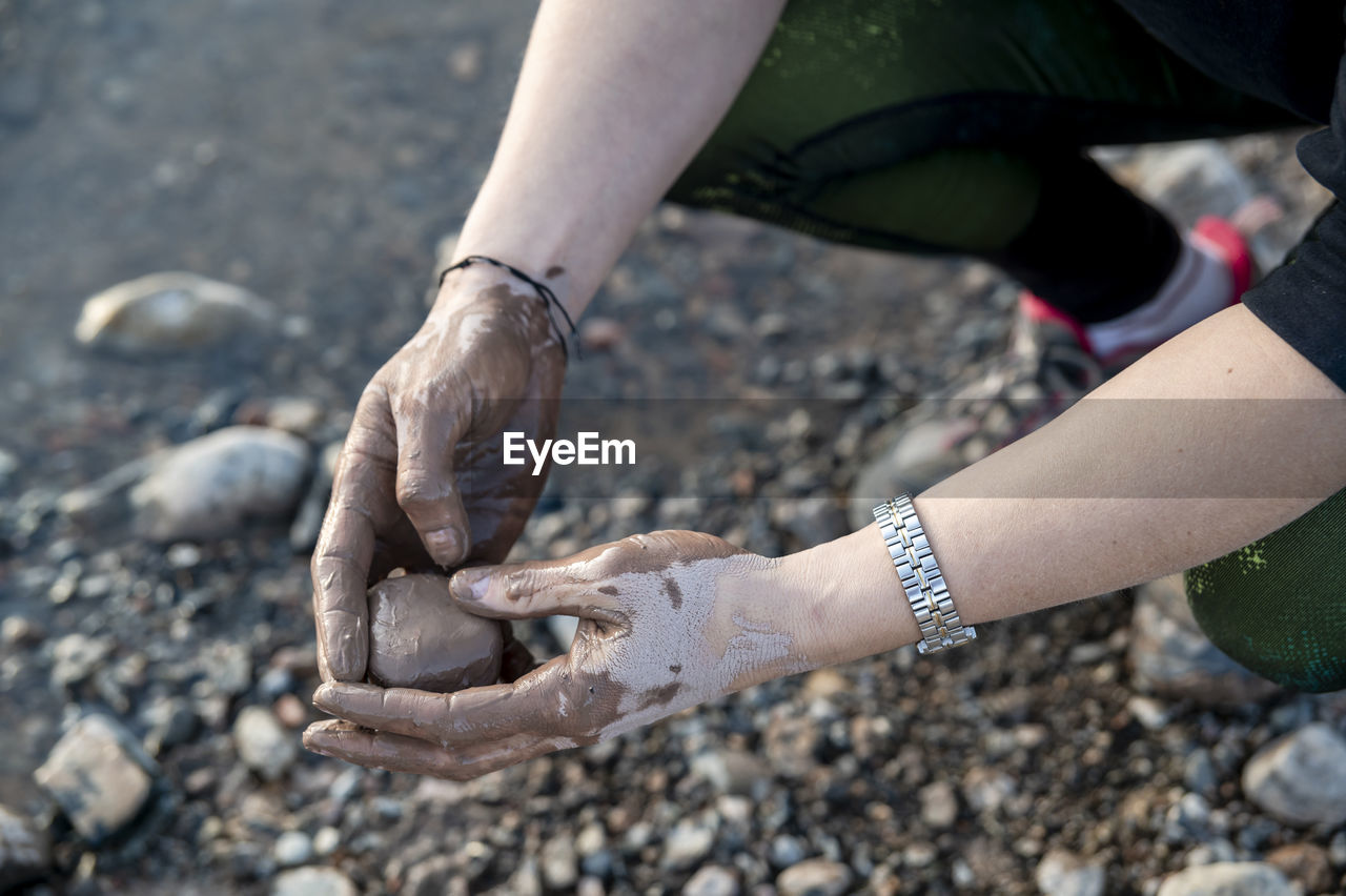 Woman putting mud on hands and face while enjoying outdoors in nature.