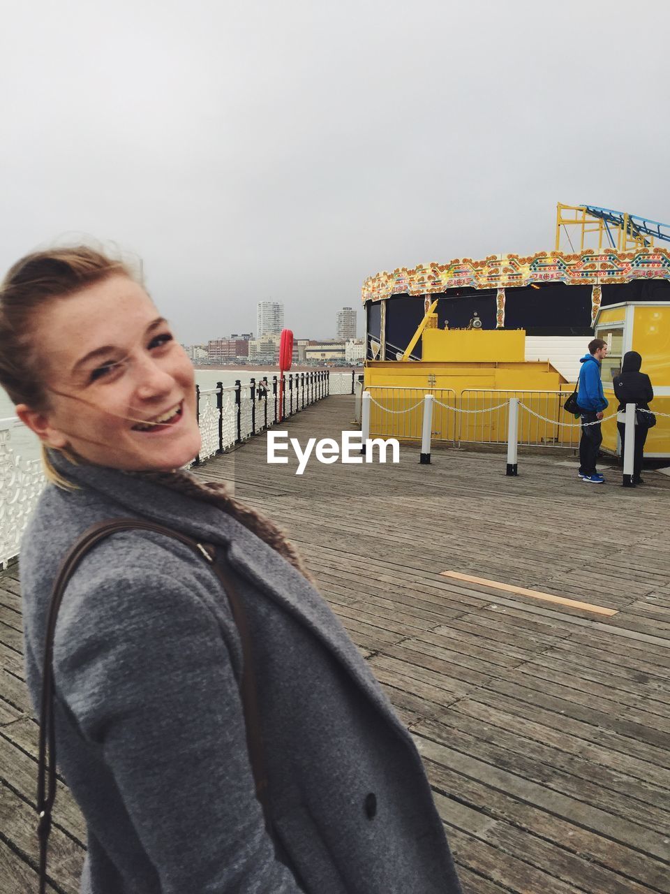 Portrait of happy woman standing at brighton pier against sky