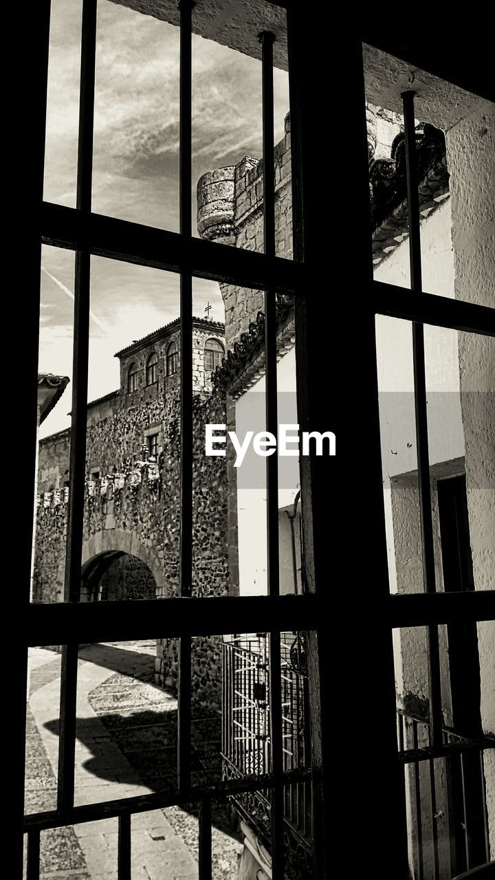 BUILT STRUCTURE AGAINST SKY SEEN THROUGH CURTAIN