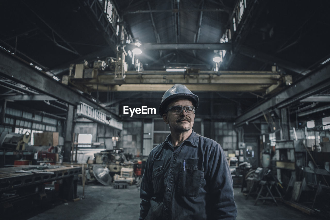 Male worker looking away while standing in metal industry