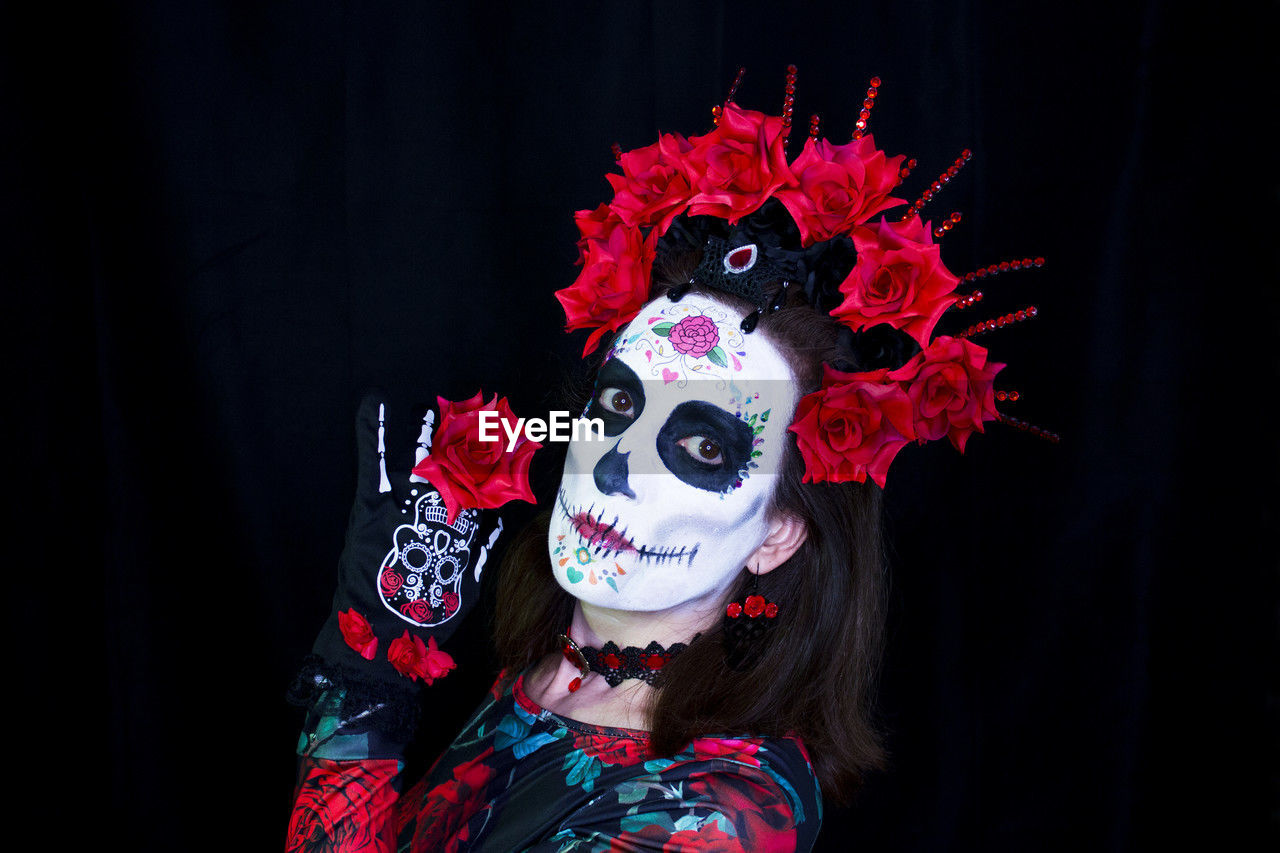 one person, performing arts, celebration, portrait, costume, disguise, mask, mask - disguise, arts culture and entertainment, adult, red, clothing, headshot, entertainment, event, face paint, performance, women, indoors, paint, black background, make-up, performing arts event, obscured face, dancing, young adult, carnival, looking at camera, person, performance art, studio shot, tradition, masque