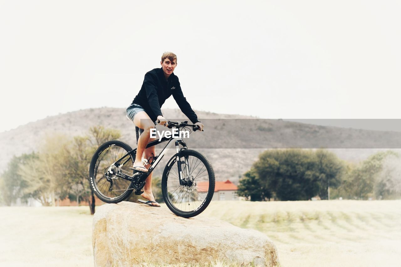 FULL LENGTH OF MAN RIDING BICYCLE ON ROAD