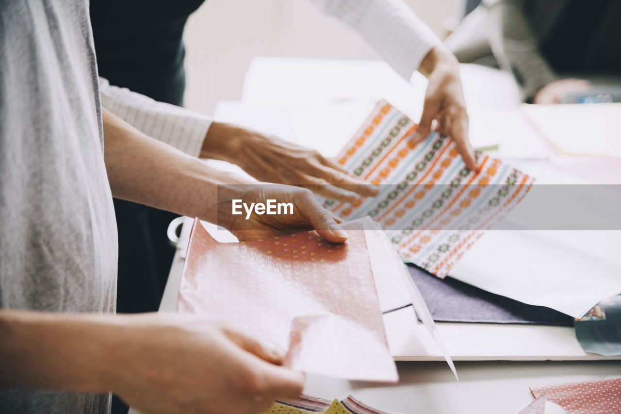 Midsection of creative businessman and businesswoman working at table in office