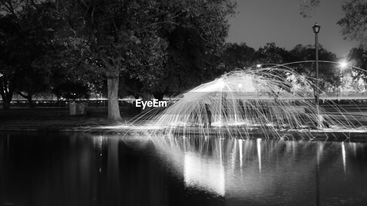 REFLECTION OF TREES IN WATER AT NIGHT