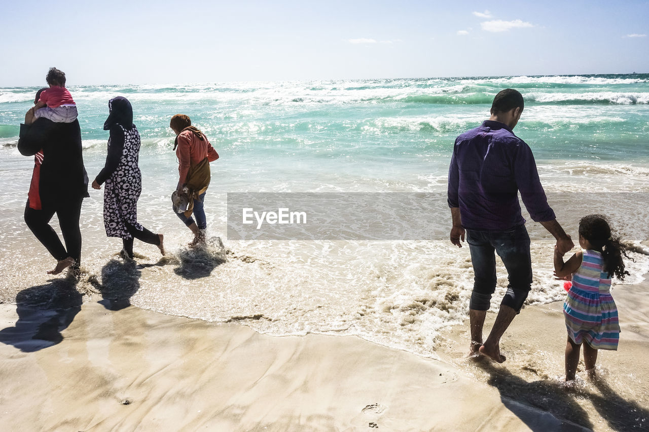 People on shore at beach during sunny day