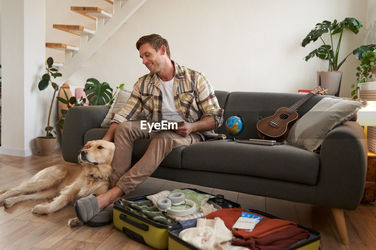 portrait of young man using mobile phone while sitting on sofa at home