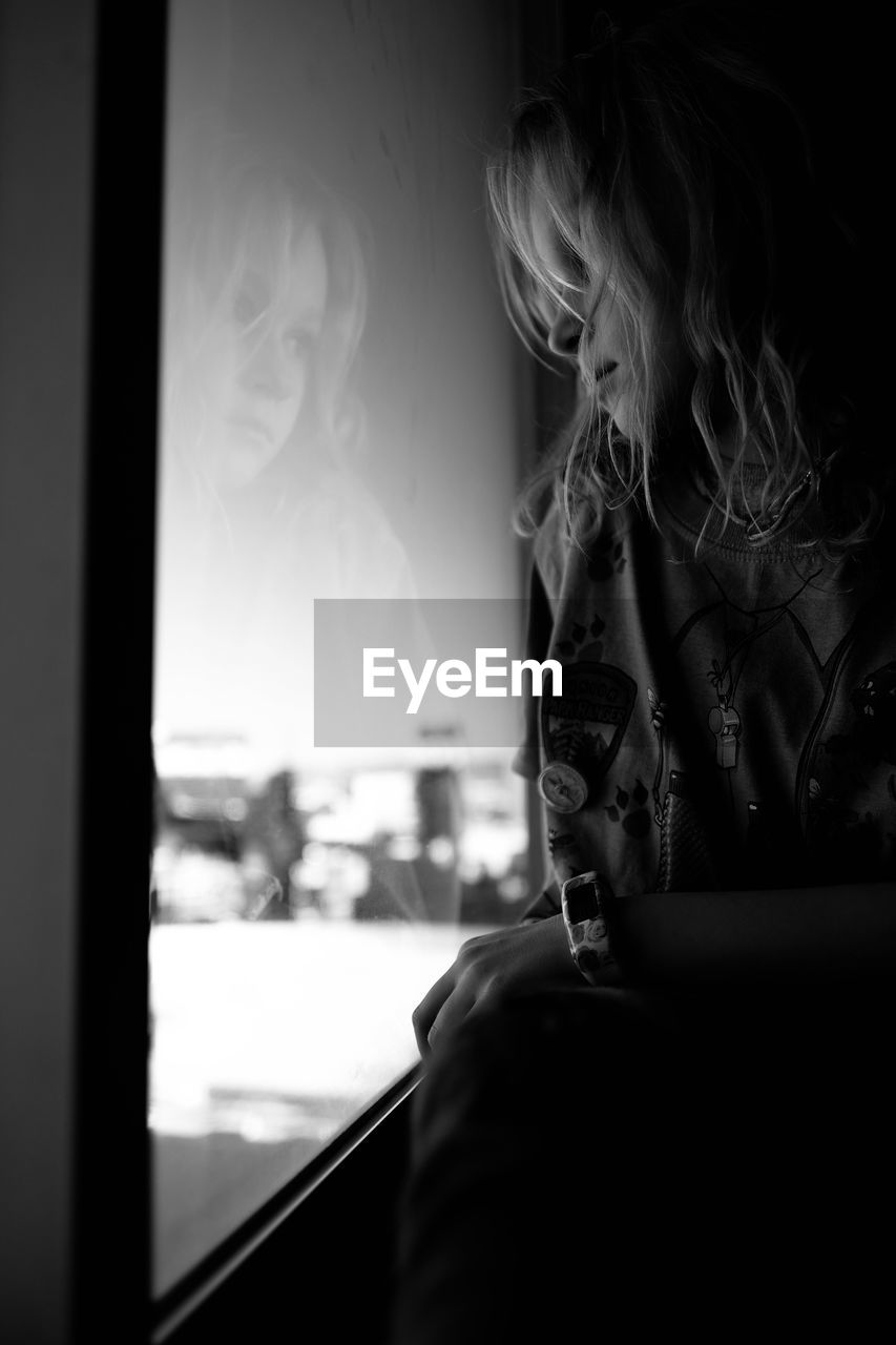 Girl looking through window at home