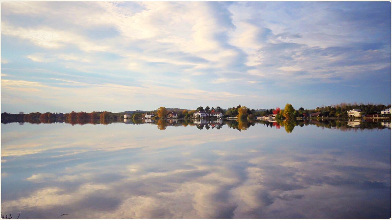 Panoramic view of trees and clouds reflecting on lake