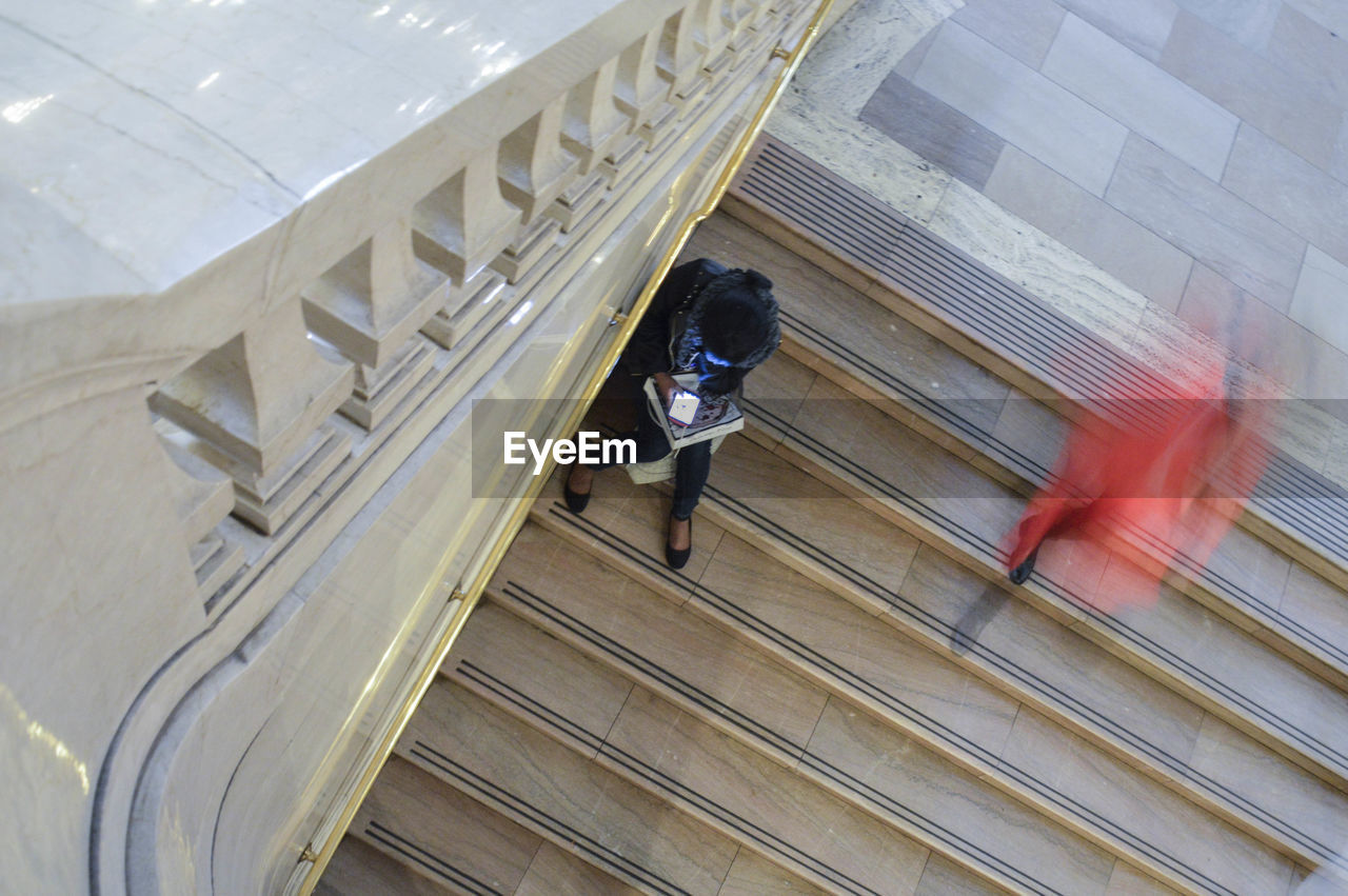 HIGH ANGLE VIEW OF MAN WALKING ON STAIRCASE