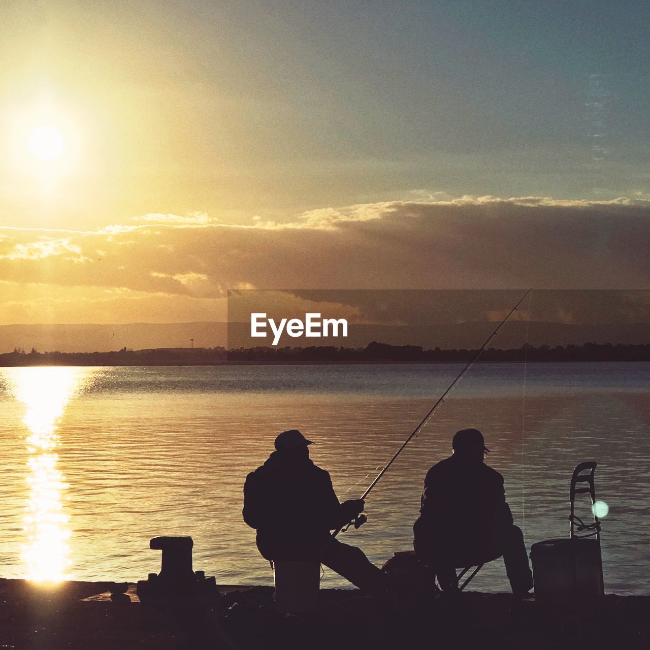 SILHOUETTE MEN FISHING AT SEA AGAINST SUNSET SKY