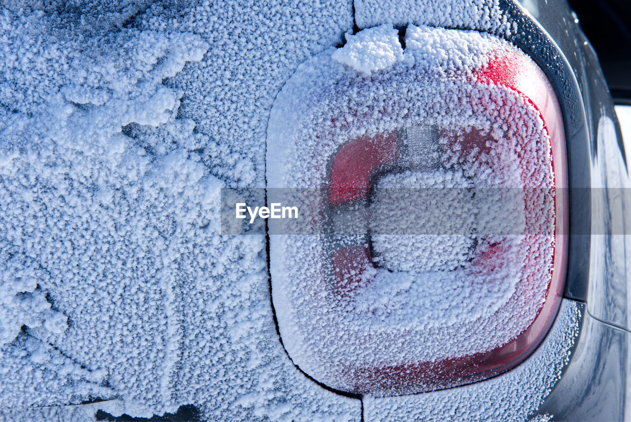 Rear tail light of car covered in snow after blizzard on winter