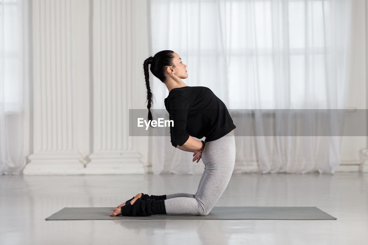 Side view of woman practicing yoga at home