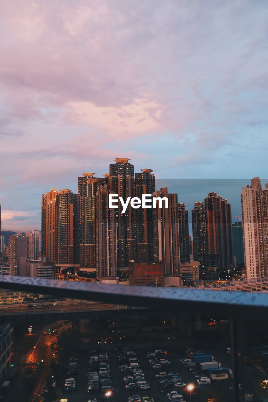 Modern buildings in city against sky during sunset