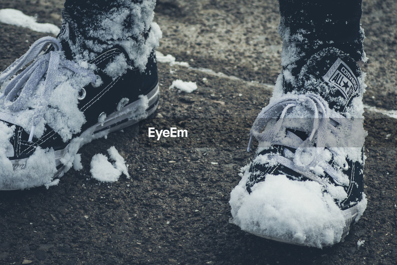 LOW SECTION OF PERSON STANDING ON SNOW COVERED GROUND