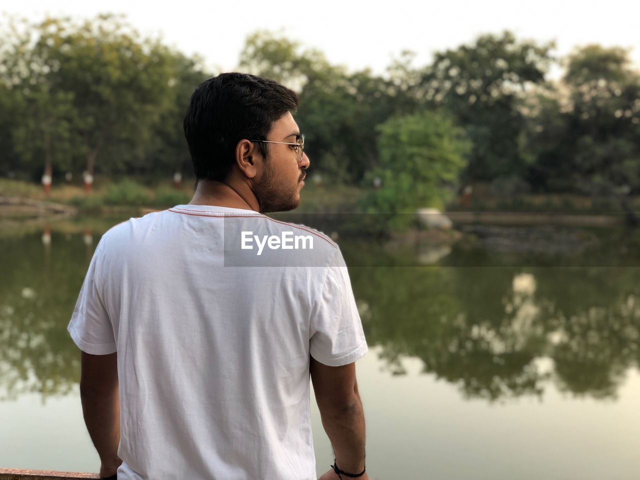 Rear view of man standing against lake