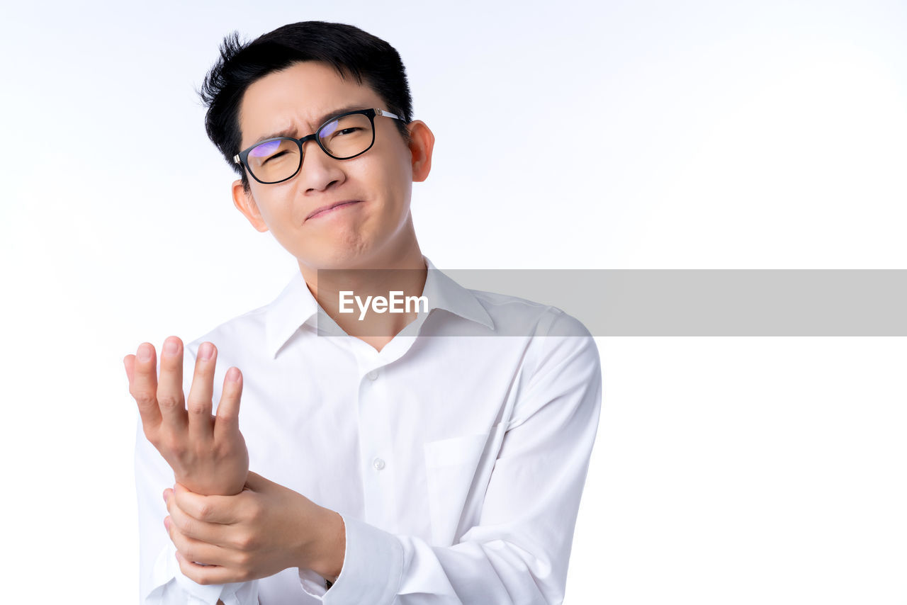 PORTRAIT OF YOUNG MAN AGAINST GRAY BACKGROUND