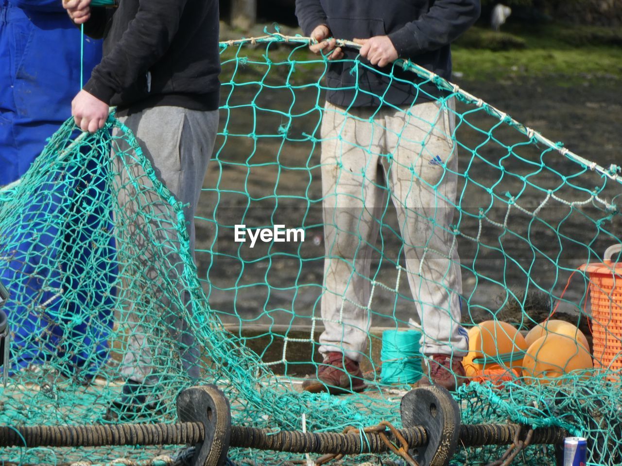 Low section of men holding fishing net while standing outdoors