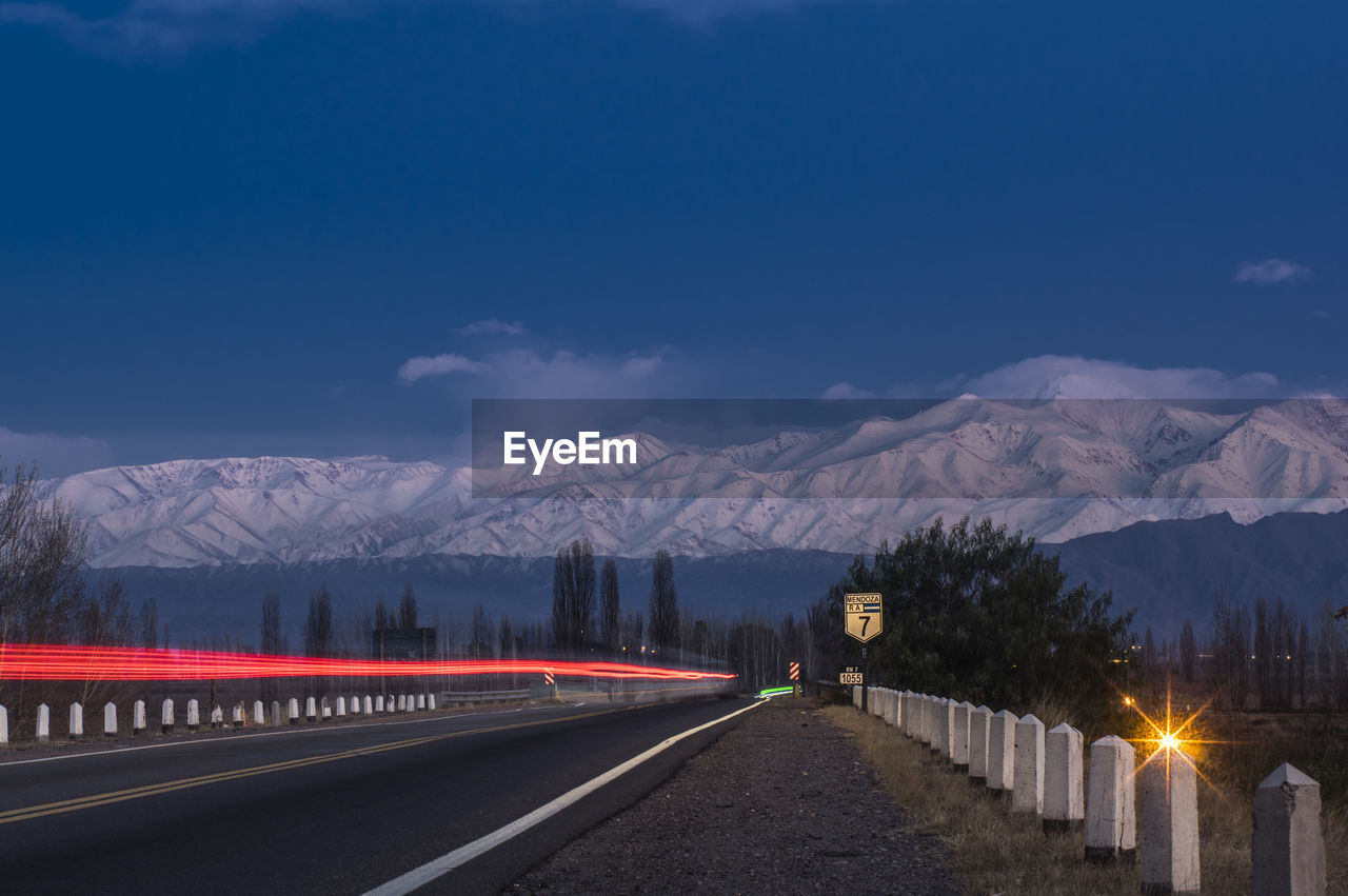 Road by snowcapped mountains against sky during winter