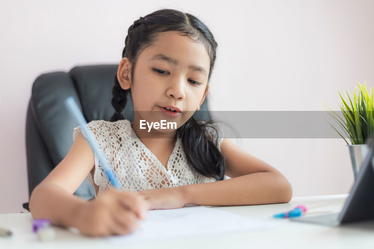 Smiling cute girl writing in book on table