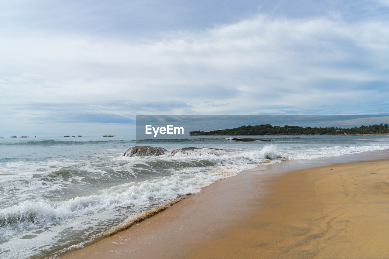 Tropical beach with palm trees. cloudy sky. arugam bay, sri lanka