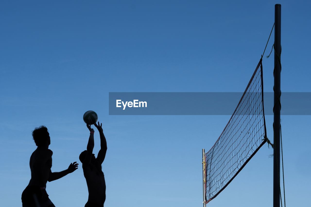 LOW ANGLE VIEW OF SILHOUETTE PEOPLE PLAYING AGAINST BLUE SKY